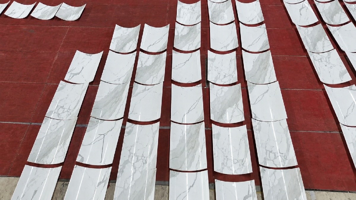 Calacatta White marble panels arranged on factory floor for curvature alignment, demonstrating pre-installation planning