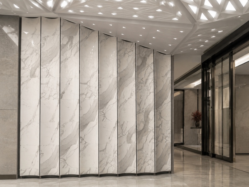 Paneles de pared curvos personalizados con aspecto de mármol blanco Calacatta para un interior comercial moderno.