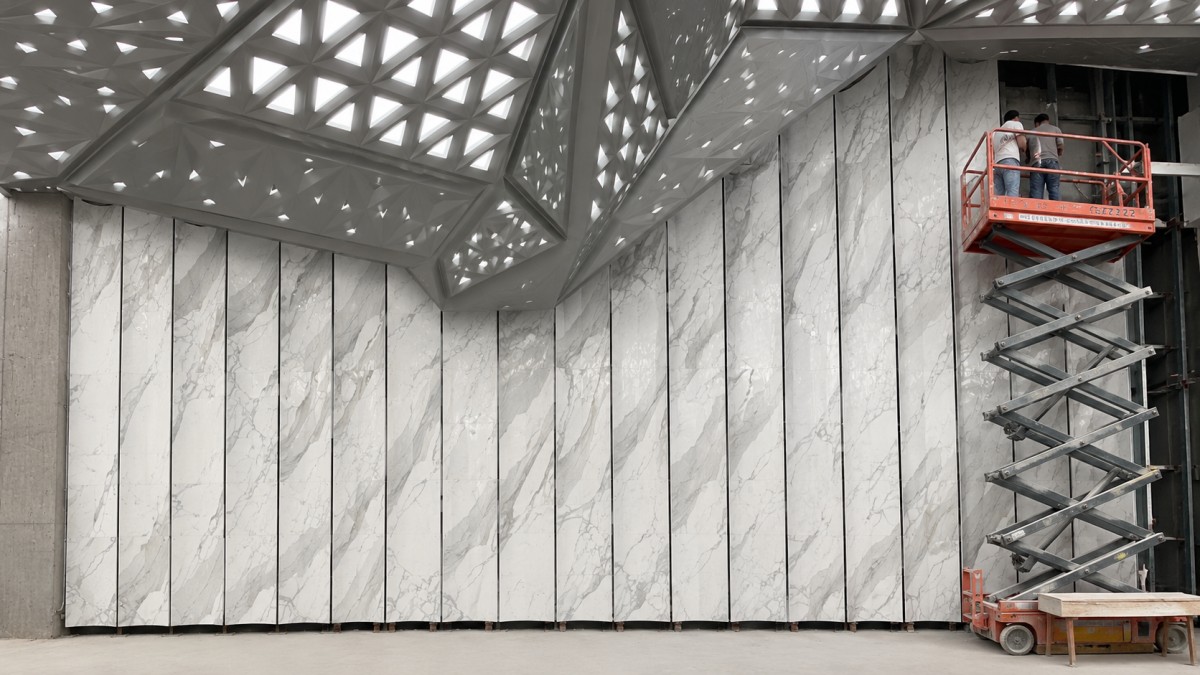 Custom curved white marble-look stone wall panels being installed in a modern commercial interior