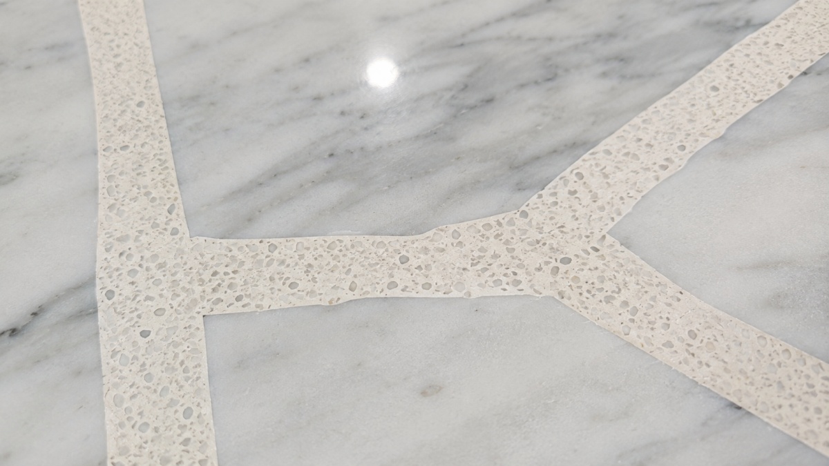 Close-up of light terrazzo inlay lines and grey white marble texture on a custom stone tabletop